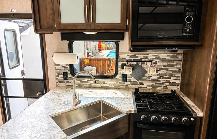 Upgraded kitchen with rich cabinetry, full stove, microwave, and deep sink