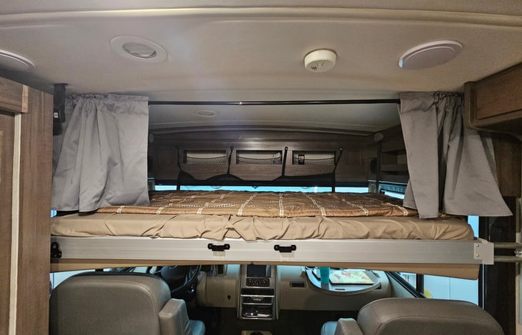 Drop down bed over driver seats, with curtain for privacy and extra storage.