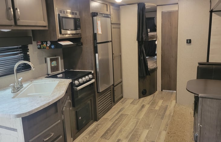 kitchen with large sinks, stove, oven, microwave, freezer, refrigerator and pantry.