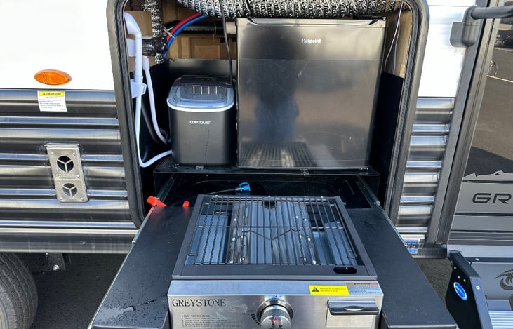 Premium outdoor kitchen with mini fridge, ice maker, grill, and outdoor shower