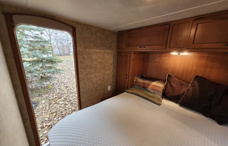 Back bedroom with queen bed, closet cabinets on both sides, storage above bed, with separate exterior door. A door separates bedroom from hallway.