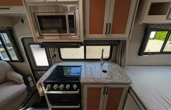 Bright, modern interior with a cute pop of color! Features a cozy rear queen bed, fully equipped kitchen, converting dinette, over-cab bunk, and an accent armchair. Clean, open, and ready for adventur