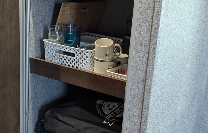 Pantry with dishes pots and pans, coffee pot, crock pot,toaster, portable blackstone griddle.