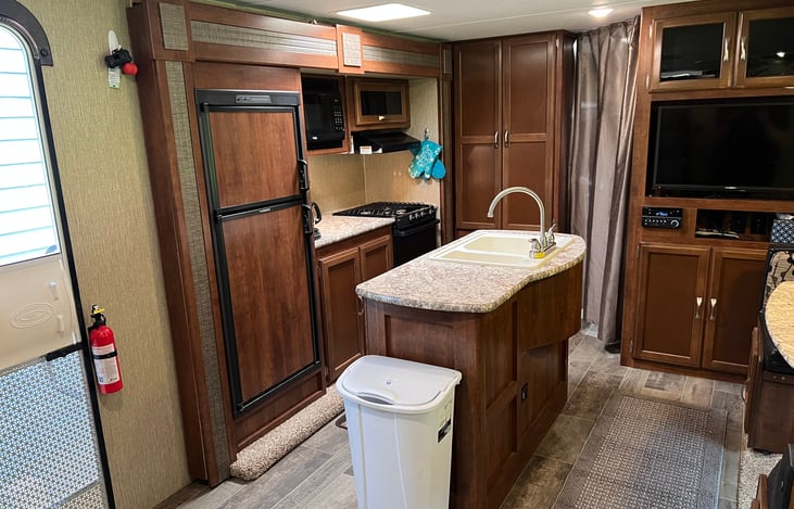 Easy to access everything you need in the kitchen. Fridge and freezer, microwave, oven, cooktop, coffee maker, hood, pantry to your right, and island sink behind you.