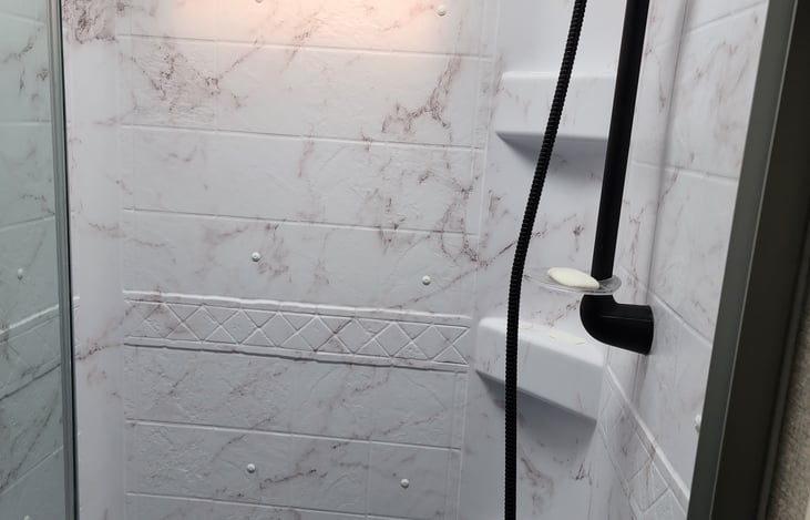 Comfortably sized shower with soap and shampoo shelves.