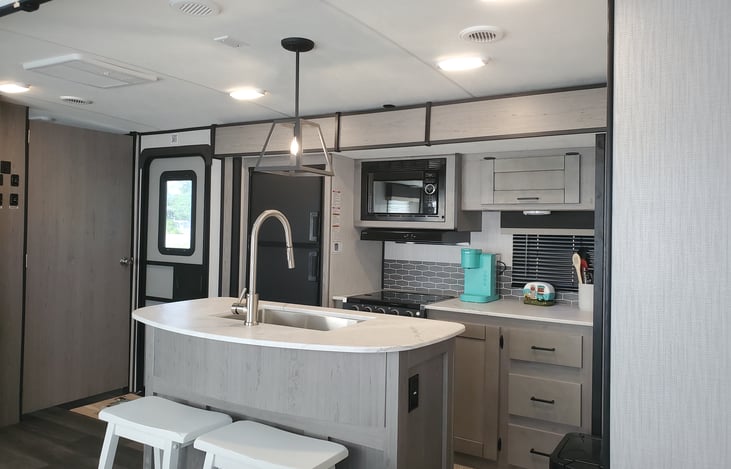 Kitchen with silverware, hand towels, pots pans, keurig coffe maker, toaster, microwave, oven, refrigerator. One roll of Paper towels.