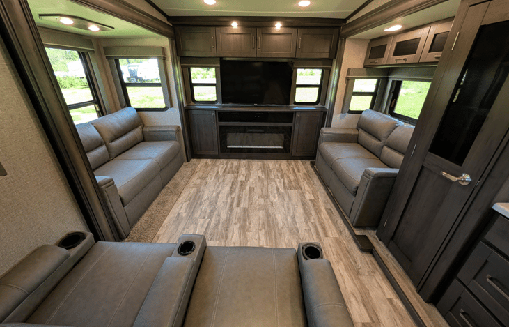 Gourmet galley & rear den retreat! Includes a 12 cu ft fridge, pantry, stove/oven, dual sofas, theater seats, 50" TV, electric fireplace, and 3 slides for spacious high-end living.