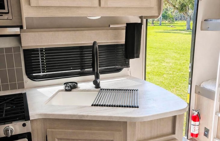 Kitchen sink with a wide window that brings in natural light and a view of the outdoors.