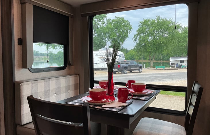 Dining table and chairs has bench seating on one site to allow for seating for four people. Table is show with place settings for three.