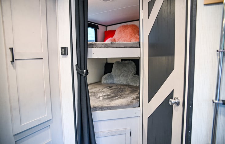 A cozy bunk room awaits, complete with comfy pillows, blankets, and a sitting-up pillow for added comfort. Perfect for kids or guests to relax and enjoy their own space.