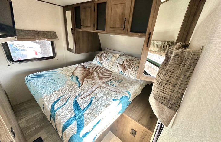 Bedroom with TV mounted inside and sliding door for added privacy. Extra storage under the bed and over head.