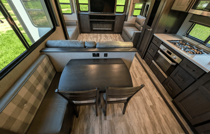 Gourmet galley & rear den retreat! Includes a 12 cu ft fridge, pantry, stove/oven, dual sofas, theater seats, 50" TV, electric fireplace, and 3 slides for spacious high-end living.