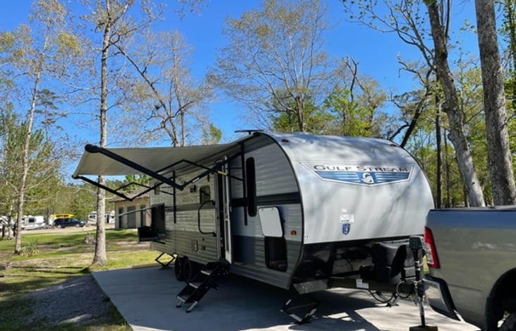 Passenger side with awning fully extended. Also featuring adjustable steps that touch the ground for stability and a handrail.
