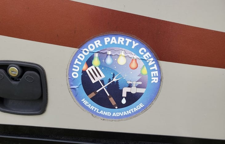 Outdoor kitchen has small fridge, sink and gas stove.