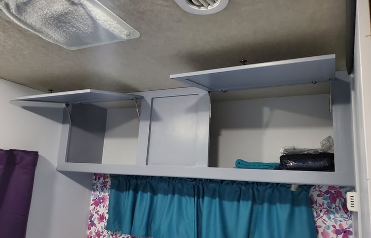 Master bedroom cupboards above bed contain sheets and extra towels