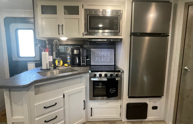 Spacious kitchen featuring cooktop, oven, fridge, coffee pot, and microwave.