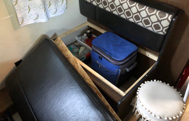 The opposite bench is also open for storage with same precautions. Be sure the board fits snug to avoid pinching or damage. This compartment also has a first aid kit and a rolling cooler for use.
