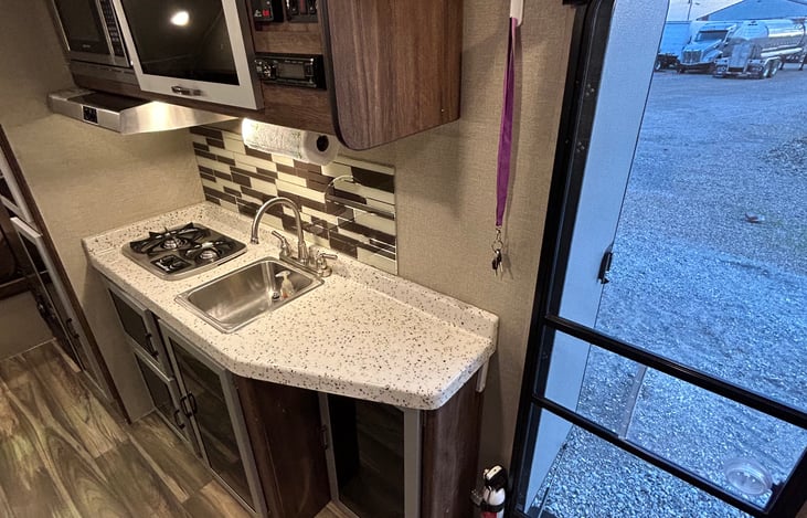 Kitchen with interior radio and control switches for slide out and tank levels - entryway view from bunkhouse