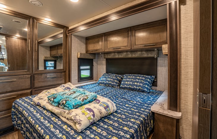 The main bedroom has a large, easy to access, bed.  The mirrors give it an open feel.  Reading lamps are above the head of the bed.