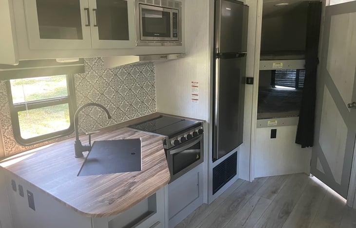 Farmhouse Kitchen complete with 3 burner stove, microwave, oven, fridge/freezer, stainless steel sink, and lots of storage above and below.