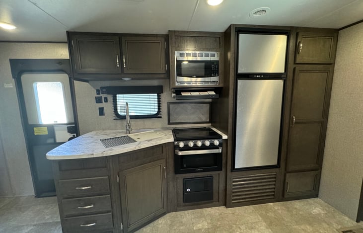 Kitchen fully stocked with cooking utensils, plates, cups, silverware, and coffee pot.  Larger sized refrigerator/freezer, spacious storage cabinets, 3-burner stove/oven, & microwave.