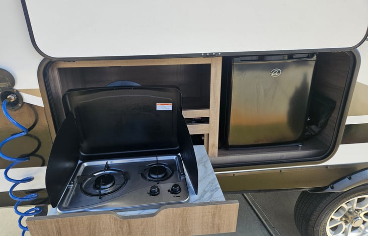 Outdoor propane stove & mini fridge; spray port conveniently located for easy clean up