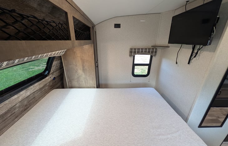 Cozy front bedroom featuring an upgraded residential mattress for a great night's sleep, TV, and bright windows with a massive automotive panoramic front view!