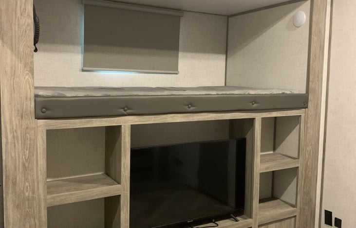 Bunk living area with single bunk and TV below.