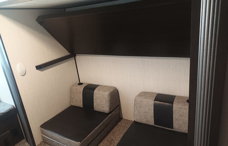 Showing the top bunk/ fixed twin bed can raise up to create more space when you're in the chairs