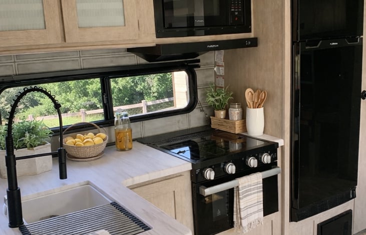 Spacious kitchen with double bowl sink, ample cupboard space, stove top with oven, built-in microwave, and refrigerator/freezer.