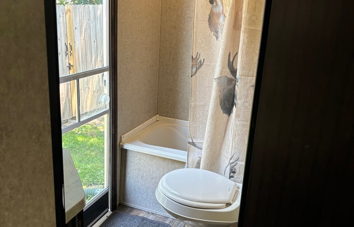 Bathroom features a small tub, and adjustable shower.
