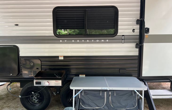 Flat grill which attaches to bracket on side of camper, also foldable storage table, both included in rental