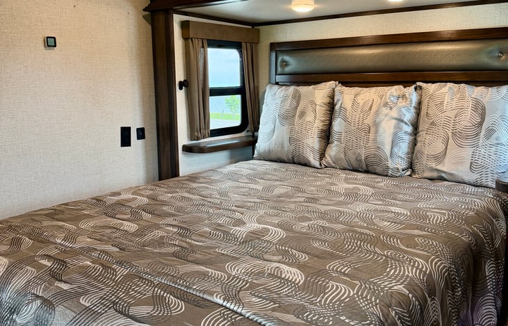 Elite Master Suite: Residential Queen-size bed slide out with dual nightstands, USB charging ports, a second HD TV, and a private bedroom electric fireplace.