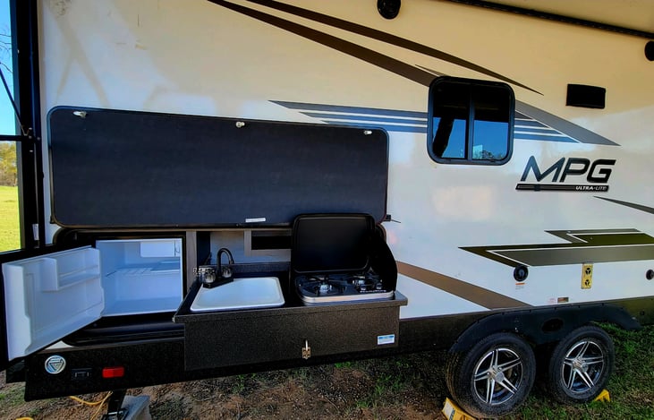 Outdoor kitchen with gas stove, fridge and sink.