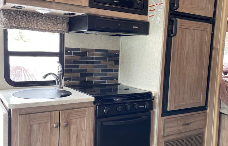 Kitchen with large sink, oven, stovetop, microwave, fridge and freezer.