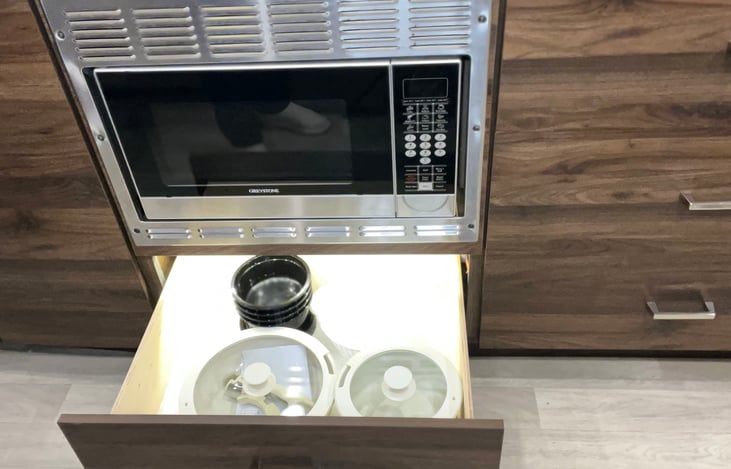 Lighted drawer under convection/microwave contains induction cookware.