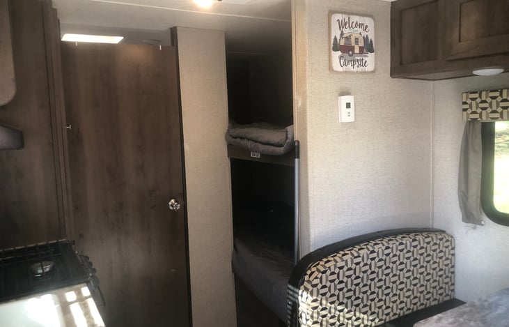 View from the kitchen counter.  Edge of dinette seat, bunk beds, bathroom door