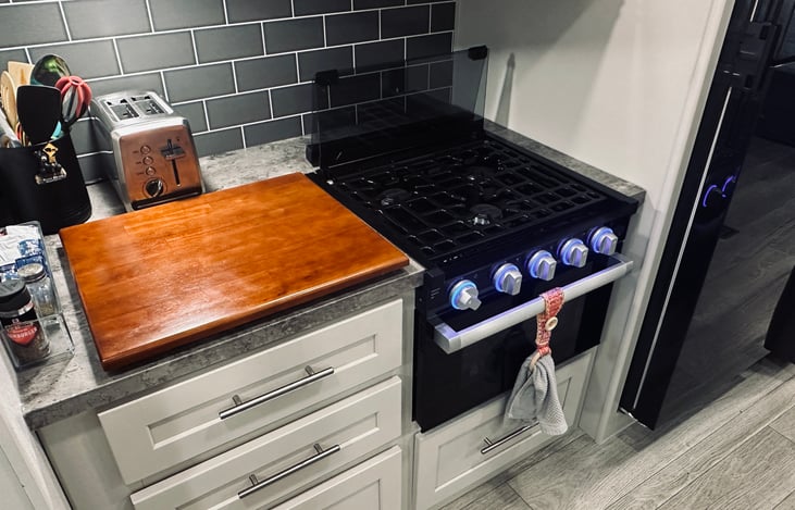 Microwave, 3-burner propane stove and oven - drawers stocked with utensils, pots and pans.