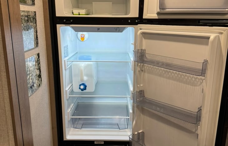 Spacious 12-volt refrigerator keeps food and drinks cold while camping, with an additional chilled water container stored inside for convenient cold drinking water.