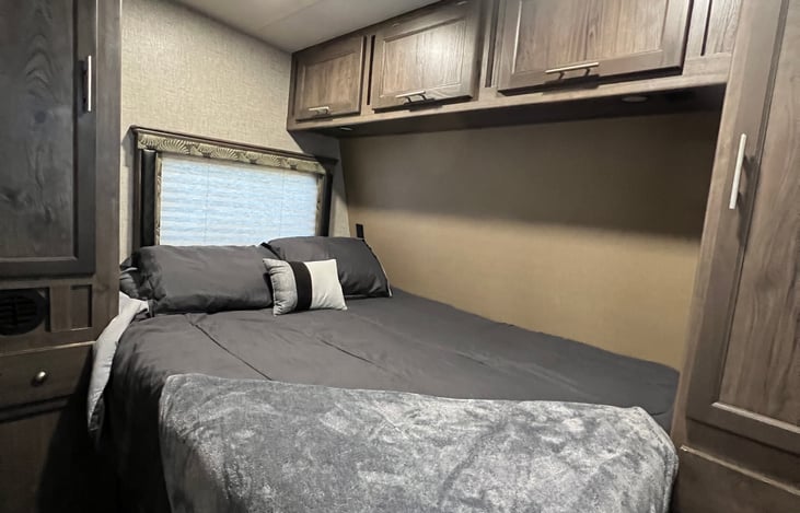 Master suite view from hallway entrance. Features two reach-in closets with hangers, overhead storage, under bed storage, bedside drawers, bedside USB charging dock and automatic Maxxair fan.