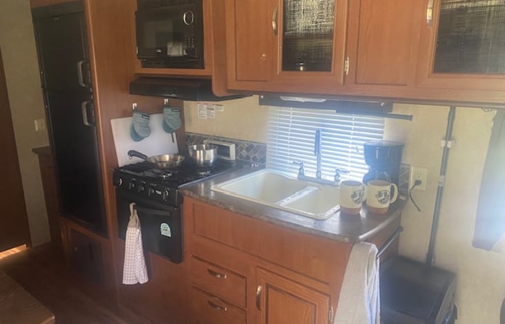 Fully stocked kitchen. Top cabinets include, tableware, pots and pans, coffee maker, hot shot water boiler. Cleaning supplies are below, with utensils in the drawers.
