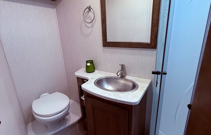 Bathroom equipped with elevated toilet for comfort, vanity sink and large mirror.
