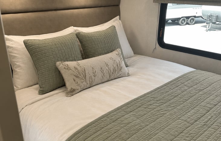 Recharge in the private rear queen bedroom featuring cozy linens, calming colors, and a door for added privacy.