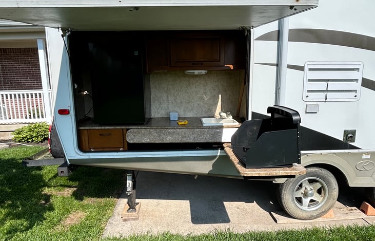Outdoor kitchen with mini fridge, 2 burner stove, sink with hot and cold water.