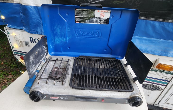Coleman grill with side burner. Uses 1# propane tanks (provided) with refill adapter to refill off 30# RV tank.