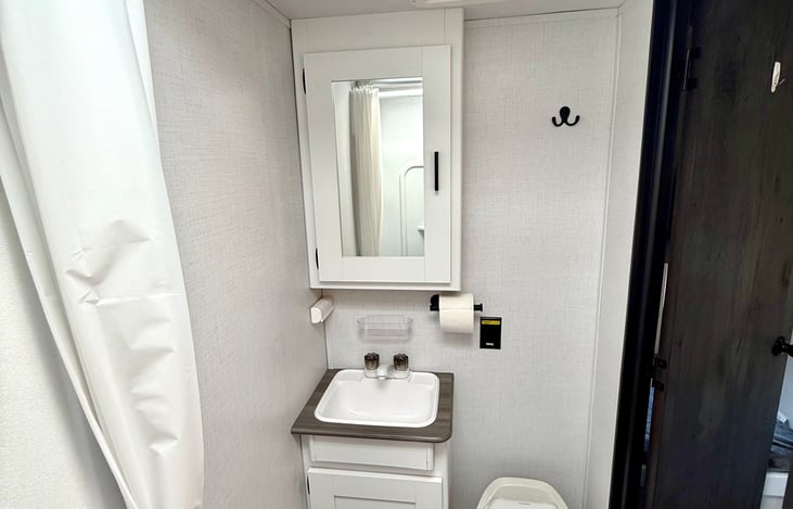 Bathroom with mirror and toilet, featuring a skylight that floods the space with natural light for a bright, airy feel.