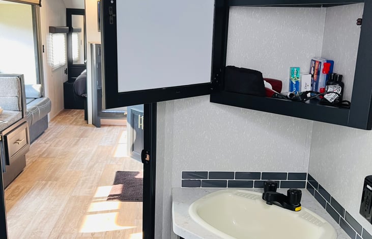 Bathroom sink and medicine cabinet stocked with fresh towels.
