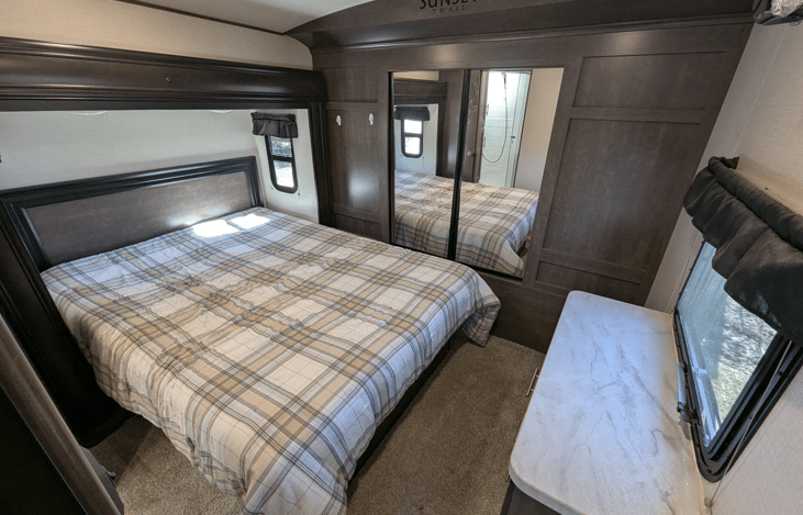 Bedroom has a slide-out creating extra space and comfort. Cozy Queen bed and ample natural light and storage.