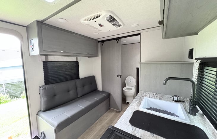 Bright, modern living space with comfortable seating. The open layout flows into a private bathroom, giving you both convenience and comfort while on the road.