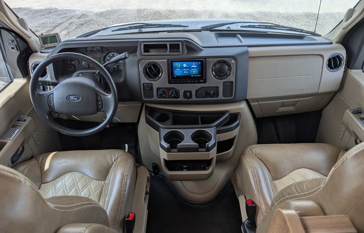 Modern dashboard with touchscreen navigation system and backup camera. Comfortable captain's chairs with quilted leather upholstery make driving a pleasure. Easy-to-reach controls and cup holders keep
